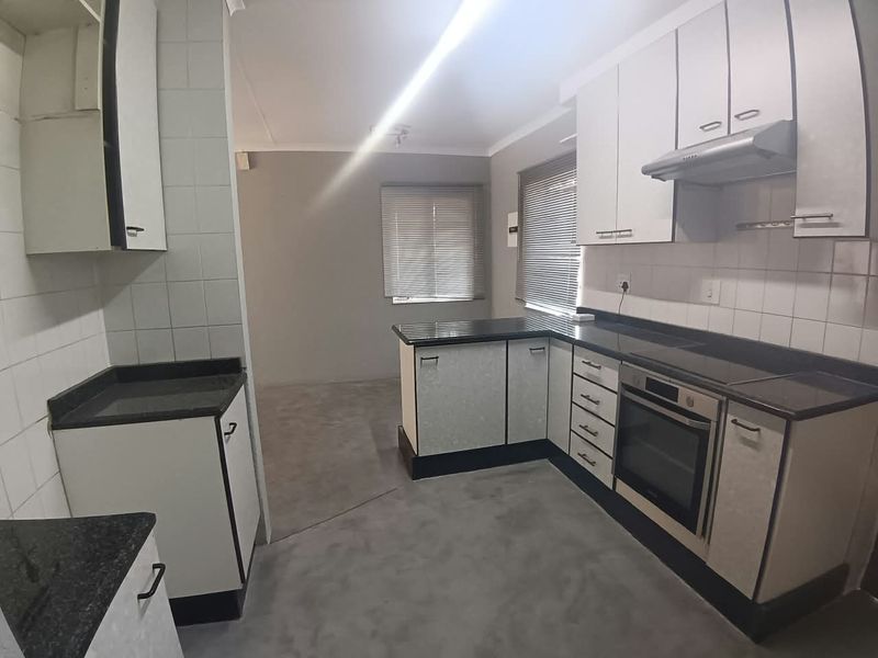 A functional kitchen featuring built-in cabinetry, granite countertops, an integrated oven, and an extractor fan, offering a clean and practical workspace.