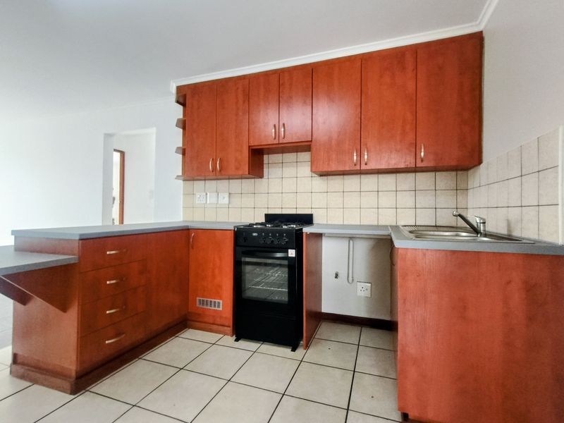 A functional kitchen featuring wooden cabinetry, a tiled backsplash, and a freestanding stove, offering a practical layout with potential for modern updates.