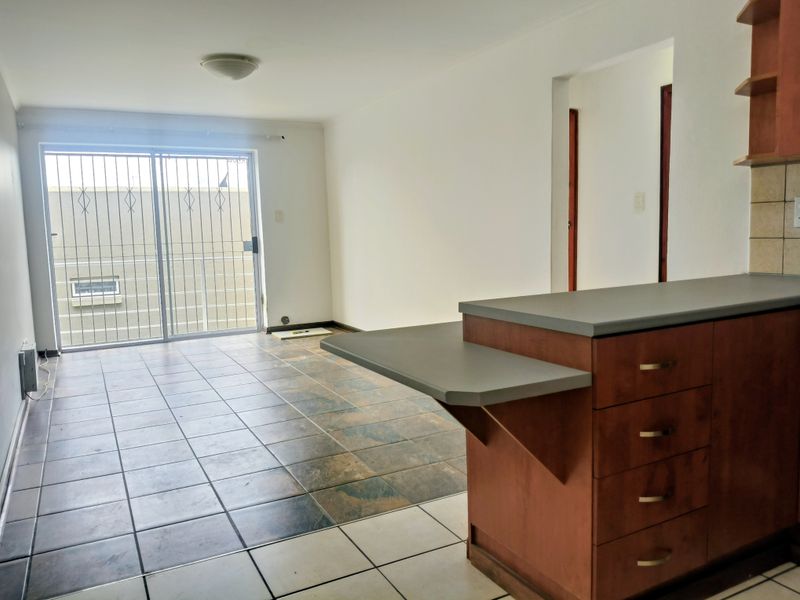 Open plan living area featuring tiled floors, a breakfast bar, and a sliding glass door leading to an outdoor space.