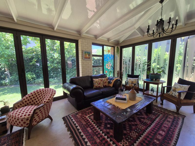 A bright and airy living room featuring exposed beam ceilings, a brick feature wall, and large bi-fold doors that open onto the garden.