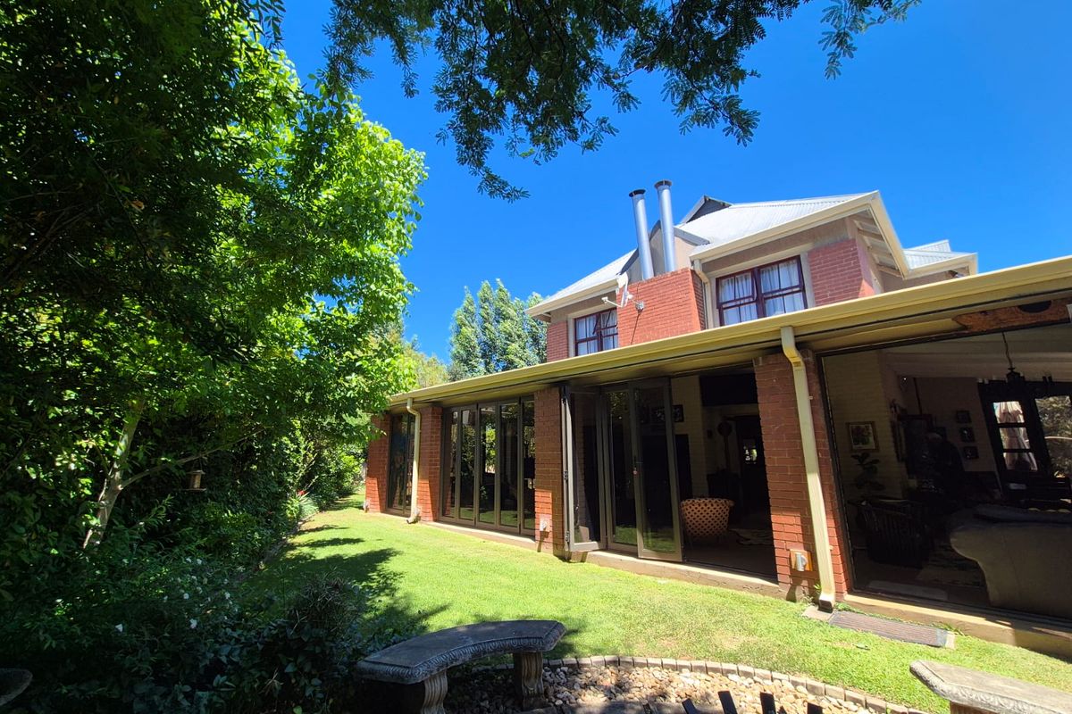 Rear view of a double-story brick house featuring a covered patio with bi-fold doors opening onto a landscaped garden.