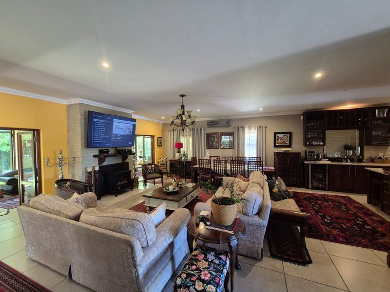Spacious open-plan living and dining area featuring a stone fireplace, tiled flooring, and integrated cabinetry, creating a warm and functional family space.