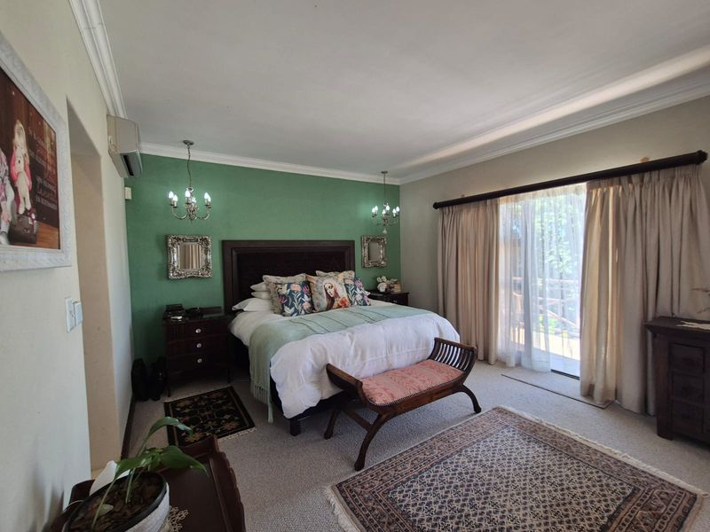 Spacious bedroom featuring a green accent wall, crown molding, and a large sliding glass door providing access to an outdoor area.