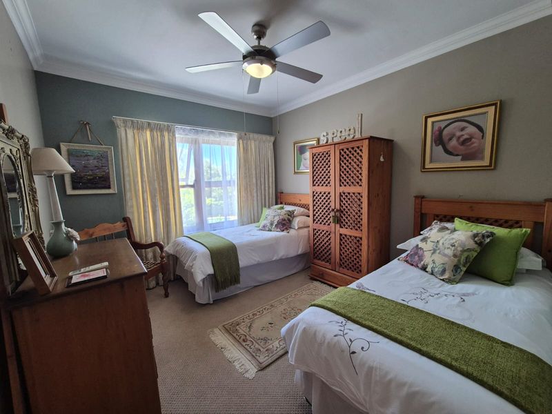 A well-maintained bedroom featuring neutral wall tones, carpeted flooring, and a central ceiling fan, providing a comfortable and functional living space.