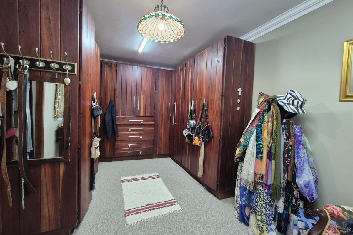 A spacious dressing room or bedroom featuring extensive floor-to-ceiling built-in wooden cabinetry, providing ample storage space with integrated drawers and hanging sections.