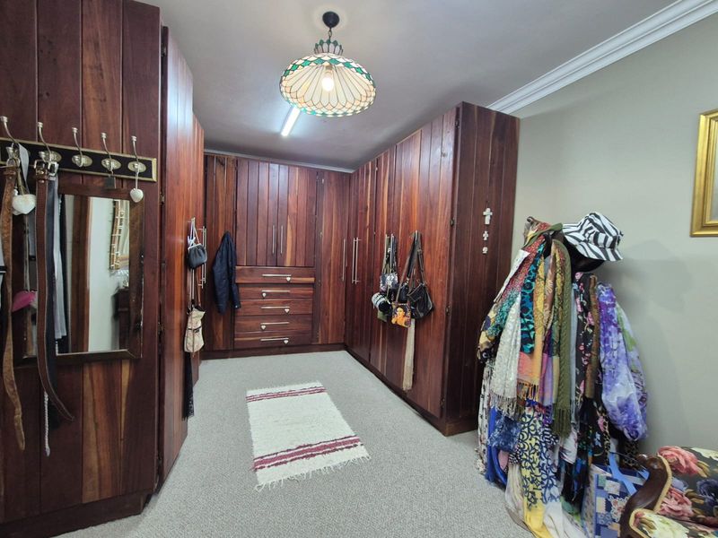 A spacious dressing room or bedroom featuring extensive floor-to-ceiling built-in wooden cabinetry, providing ample storage space with integrated drawers and hanging sections.
