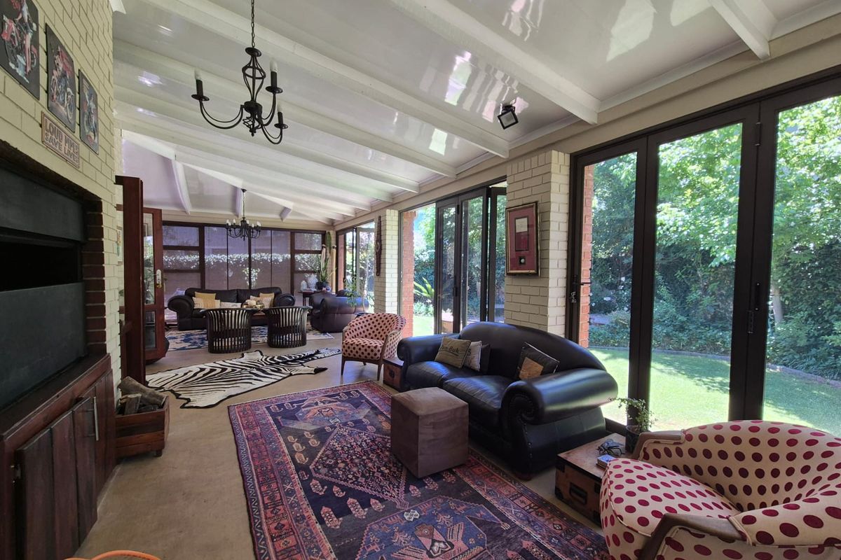 Spacious sunroom featuring exposed beam ceilings, a built-in fireplace, and large glass sliding doors that provide seamless access to the garden.