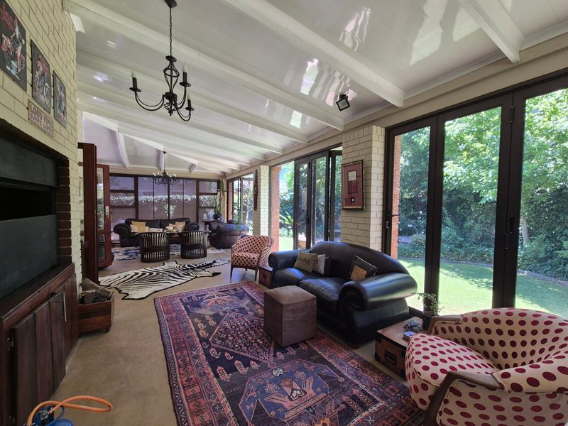 Spacious sunroom featuring exposed beam ceilings, a built-in fireplace, and large glass sliding doors that provide seamless access to the garden.