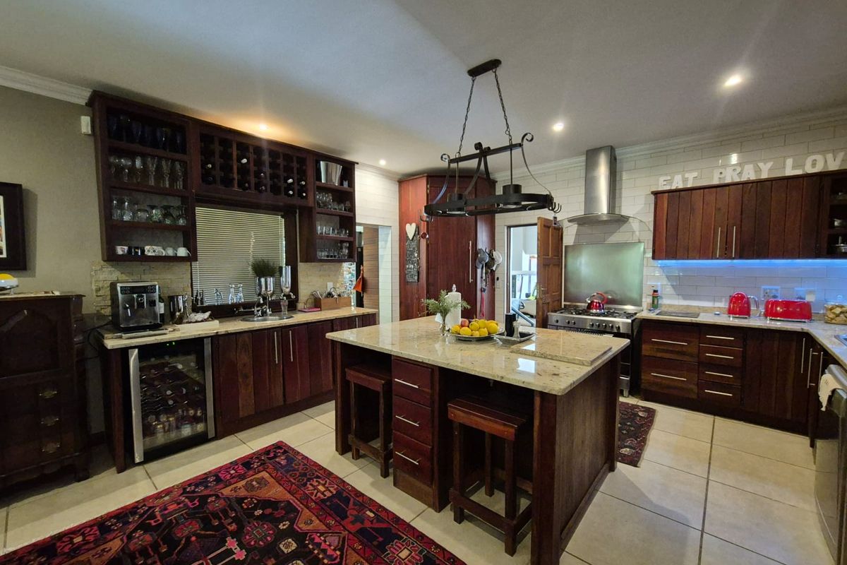 Spacious kitchen featuring dark wood cabinetry, granite countertops, a central island, and integrated appliances including a wine cooler and stainless steel stove.