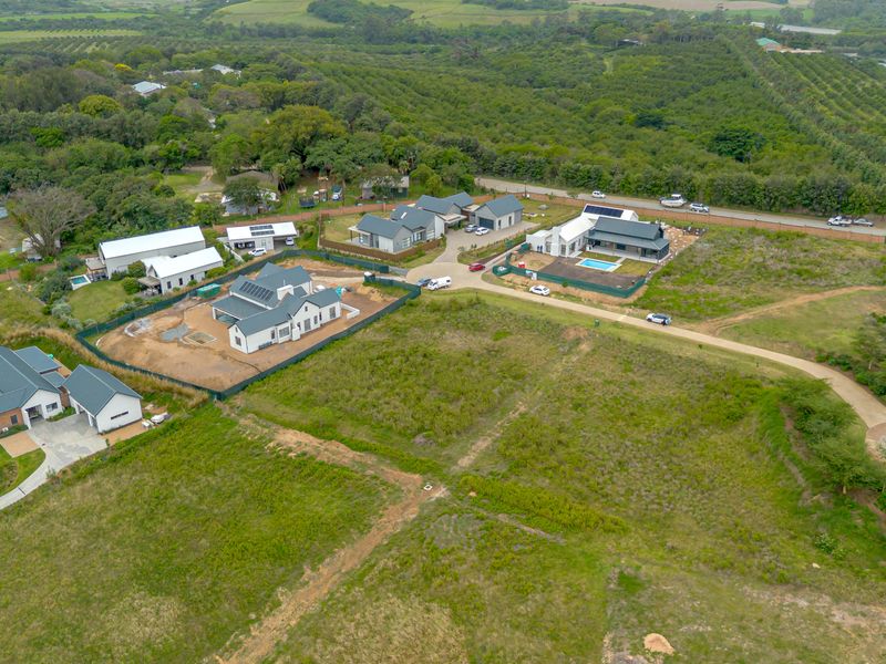 An aerial view of a residential estate featuring vacant land plots and newly constructed modern homes with paved access roads.