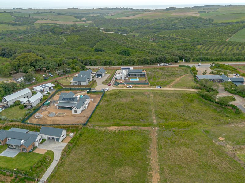 Aerial view of a residential development site featuring vacant plots, established homes, and surrounding green landscape.