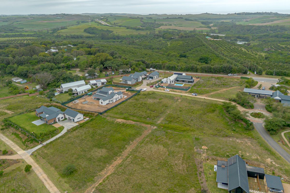 Aerial view of a residential estate featuring modern homes, paved access roads, and surrounding natural landscape.