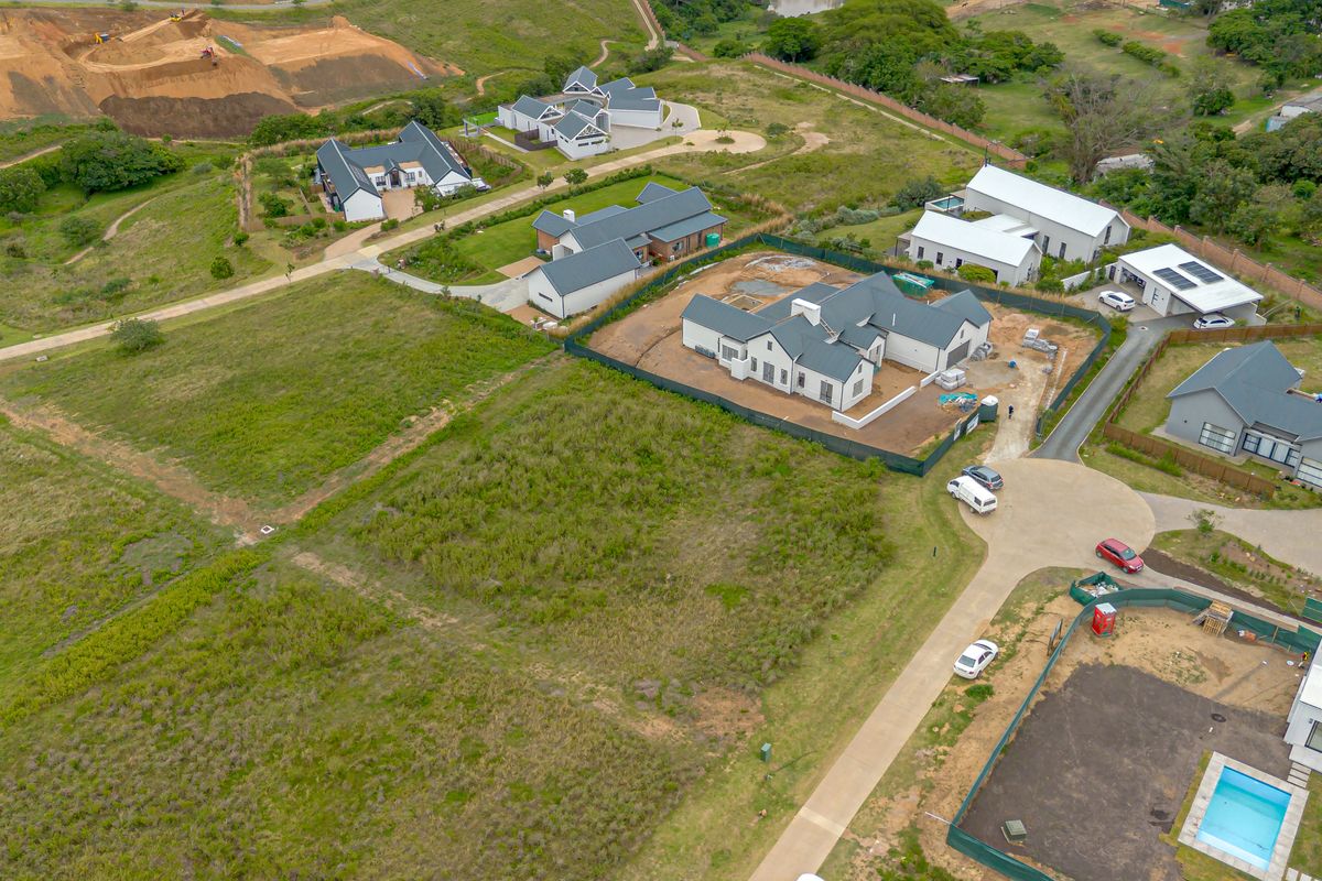 Aerial view of a vacant residential plot within a developed estate, featuring surrounding homes and established infrastructure.