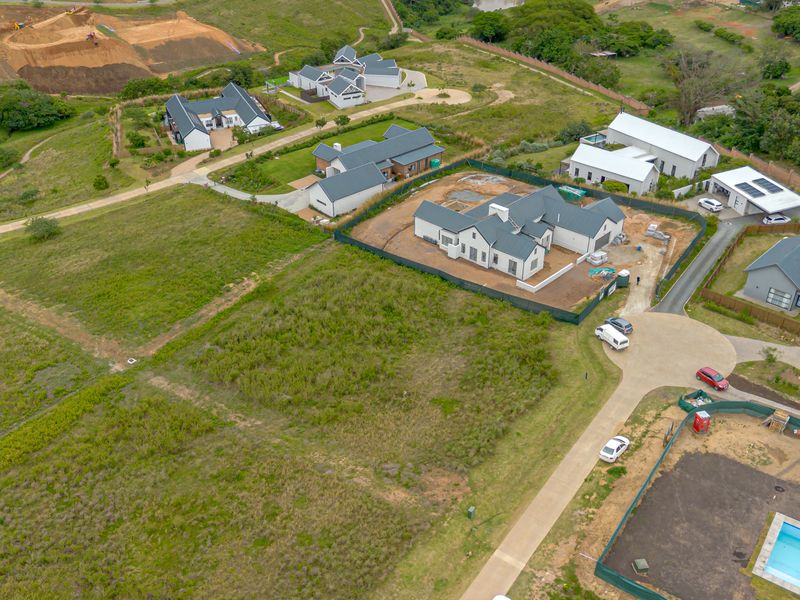 Aerial view of a vacant residential plot within a developed estate, featuring surrounding homes and established infrastructure.