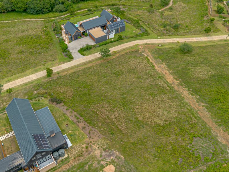 Aerial view of a vacant residential plot situated within a developed estate, featuring established access roads and surrounding modern residential properties.