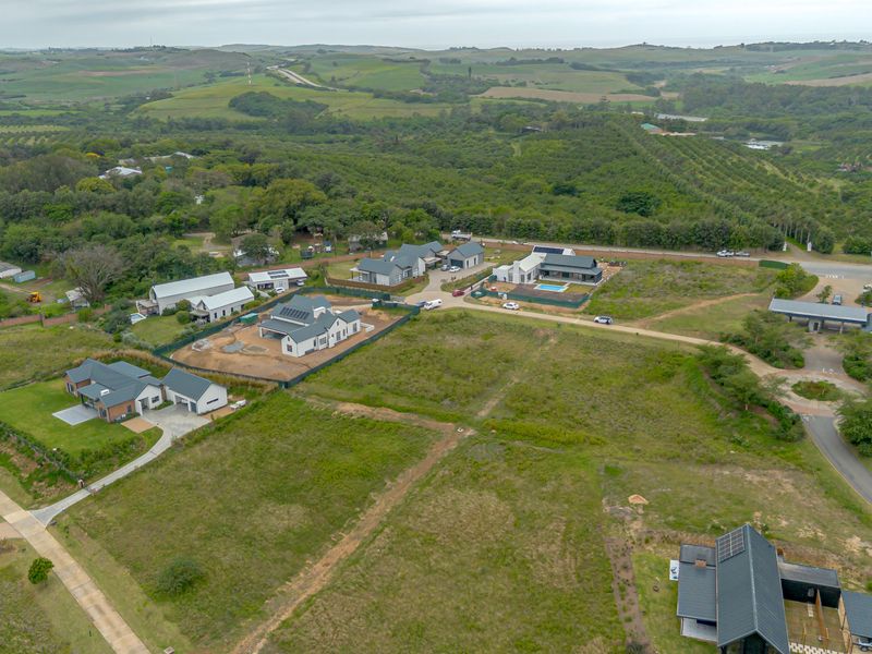 Aerial view of a residential estate featuring modern homes, paved access roads, and surrounding natural landscape.