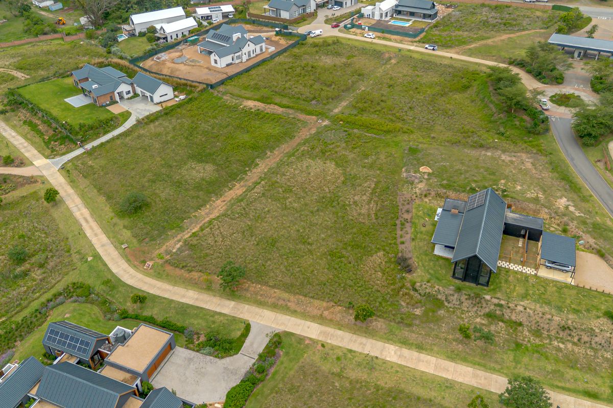 Aerial view of a vacant residential plot situated within a developed estate, featuring established access roads and neighboring modern homes.
