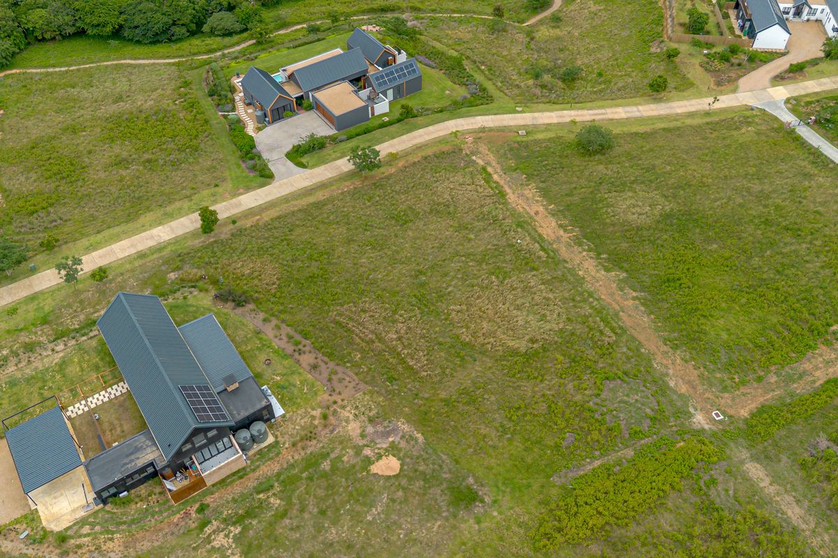 Aerial view of a residential vacant land plot situated within a developed estate, featuring surrounding modern homes and established access roads.