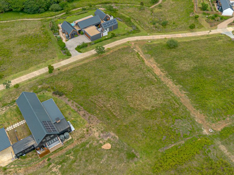 Aerial view of a residential vacant land plot situated within a developed estate, featuring surrounding modern homes and established access roads.