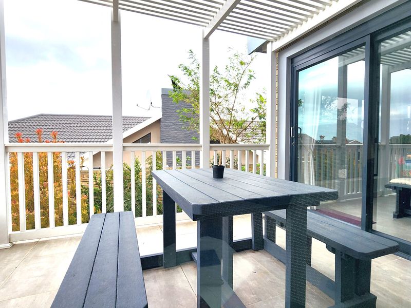 A covered patio area featuring a slatted pergola, tiled flooring, and sliding glass doors providing access to the interior living space.