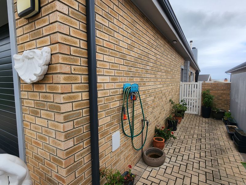 A side walkway featuring face brick walls, paved flooring, and a secure side gate leading to the rear of the property.