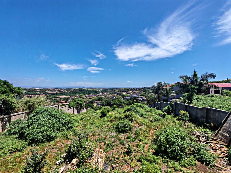 Elevated view overlooking a residential neighborhood and surrounding landscape from a vacant plot of land.