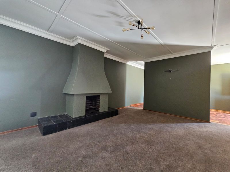 Spacious living room featuring a prominent fireplace with a tiled hearth, crown molding, and neutral wall tones, offering a blank canvas for interior design.