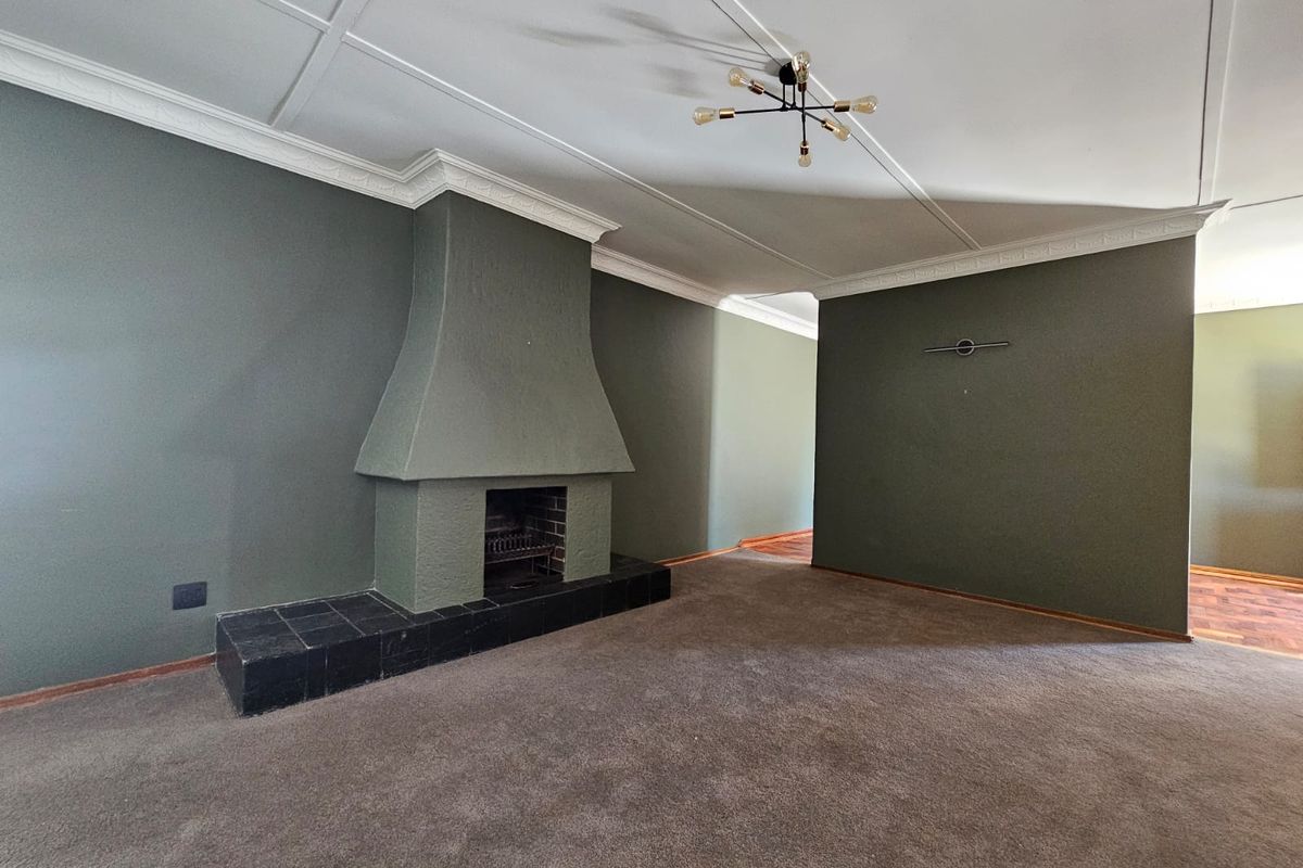 Spacious living room featuring a prominent fireplace with a tiled hearth, crown molding, and neutral wall tones, offering a blank canvas for interior design.