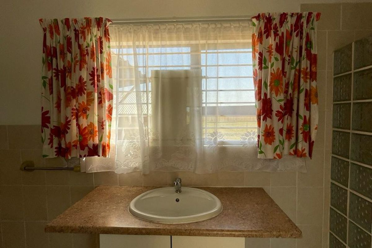 A functional bathroom vanity area featuring a built-in sink, tiled splashback, and a glass block partition wall.