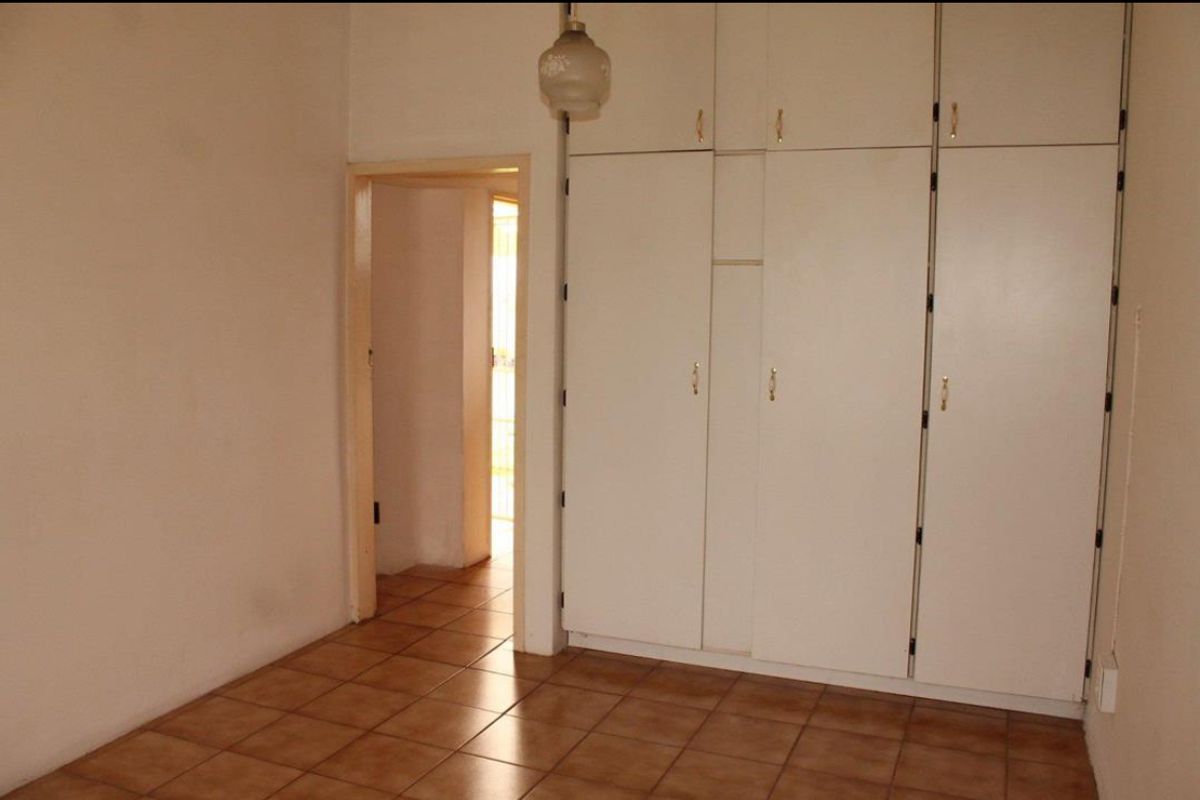 A bedroom featuring built-in floor-to-ceiling cabinetry and tiled flooring, providing functional storage space.