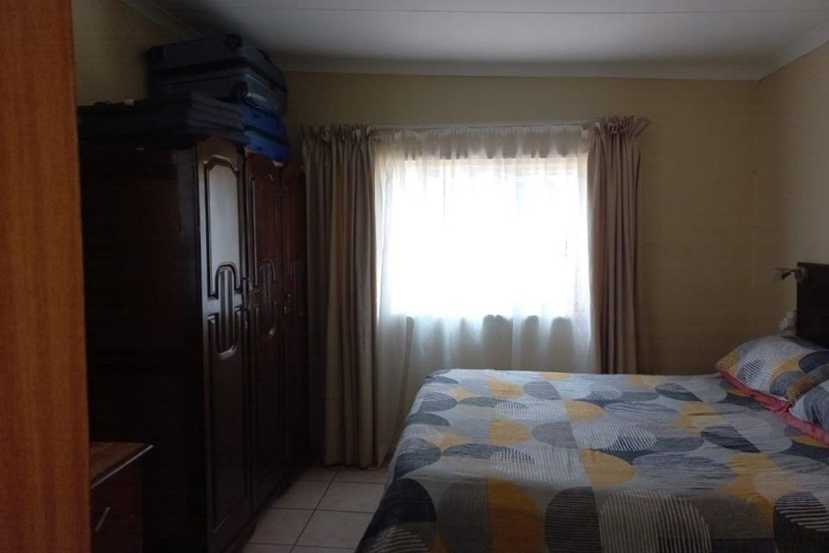 A standard bedroom featuring tiled flooring and a coved ceiling, with a window providing natural light.