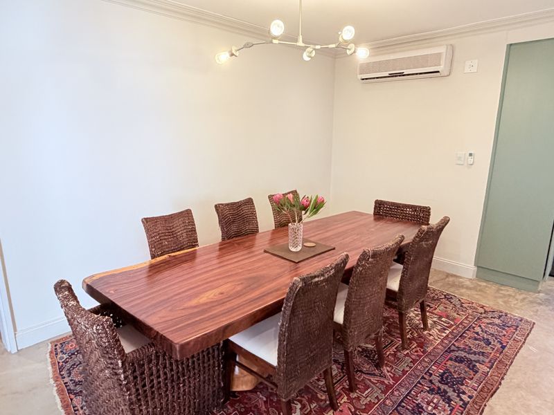A well-maintained dining room featuring tiled flooring, crown molding, and a wall-mounted split-system air conditioner.
