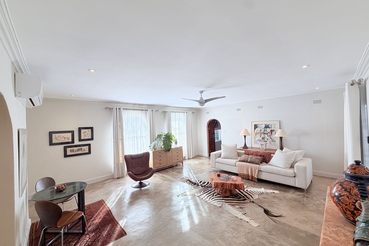 Spacious living room featuring polished concrete floors, recessed downlights, a ceiling fan, and a wall-mounted air conditioning unit.