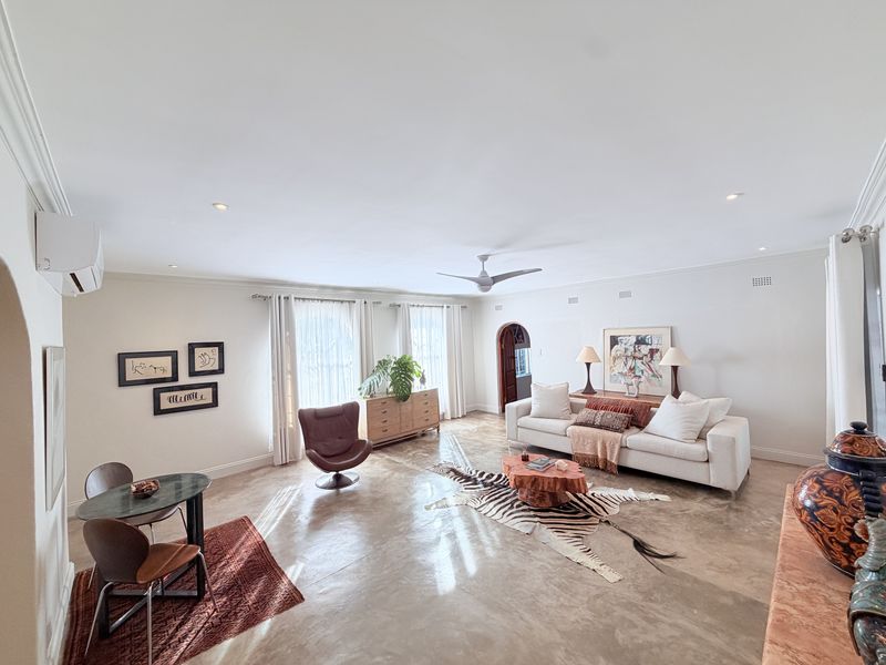 Spacious living room featuring polished concrete floors, recessed downlights, a ceiling fan, and a wall-mounted air conditioning unit.
