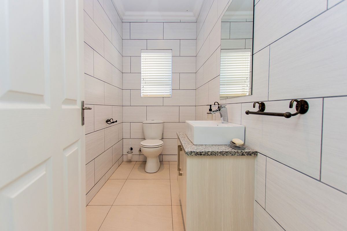 A modern, well-maintained bathroom featuring tiled walls, a vanity with a basin, and a toilet.