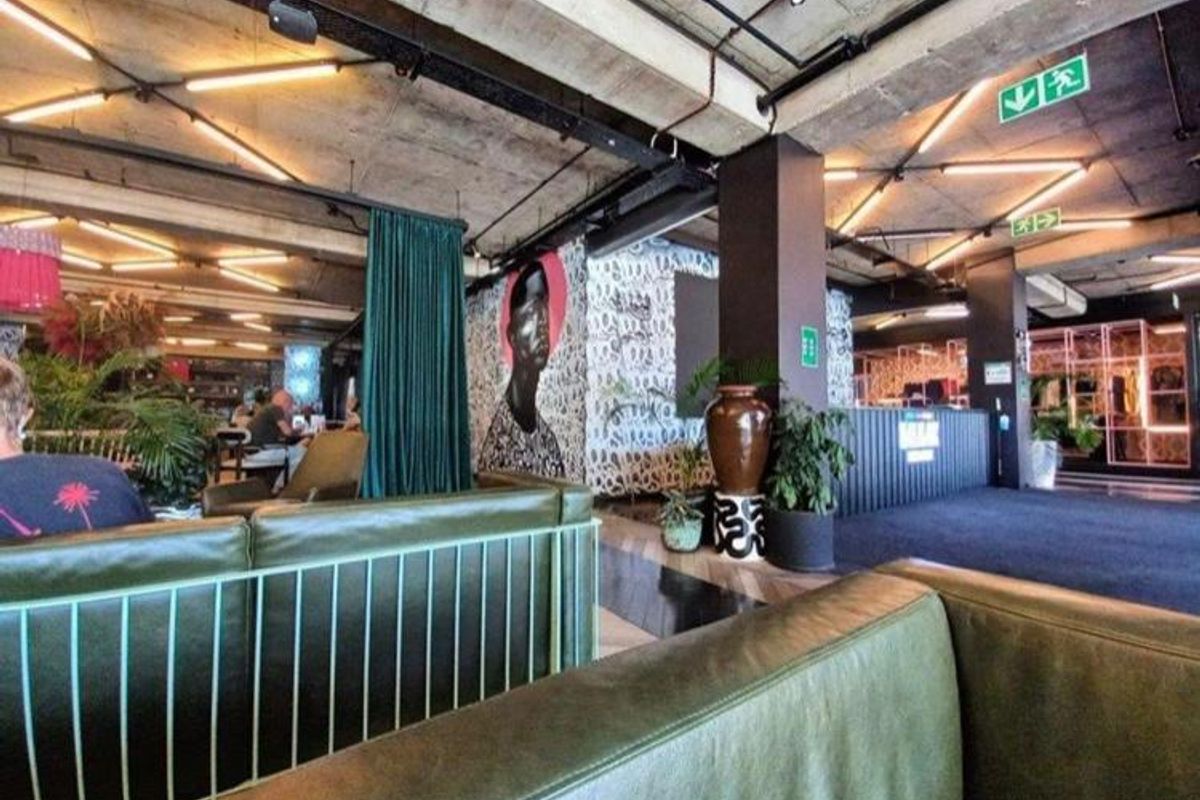 A modern open-plan living area featuring an industrial aesthetic with exposed concrete ceilings, track lighting, and structural columns.