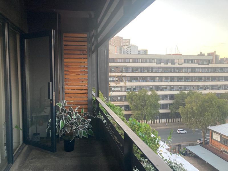 A private balcony featuring a timber privacy screen, metal railing, and direct access to the interior through a sliding glass door.