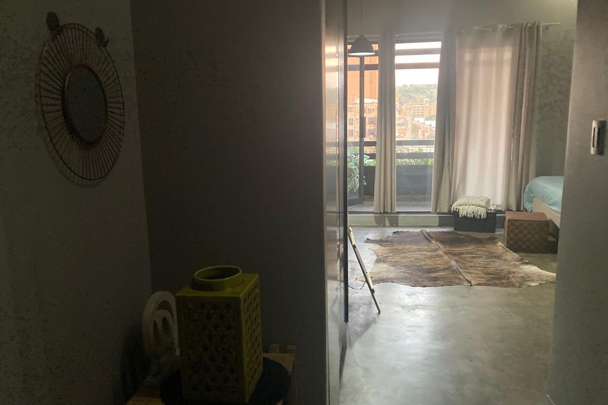 Bedroom featuring polished concrete flooring and direct access to a private balcony through sliding glass doors.