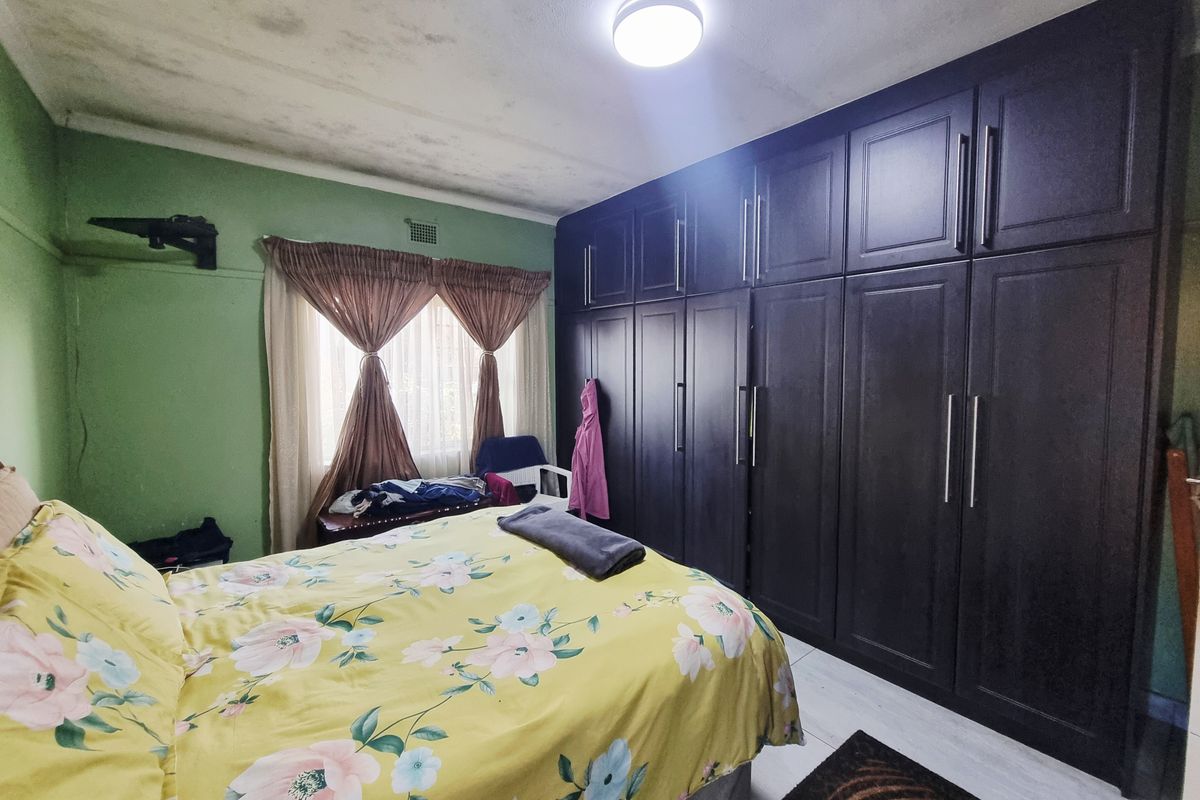 Bedroom featuring extensive dark wood built-in cabinetry and laminate flooring, requiring ceiling repairs due to visible water damage.