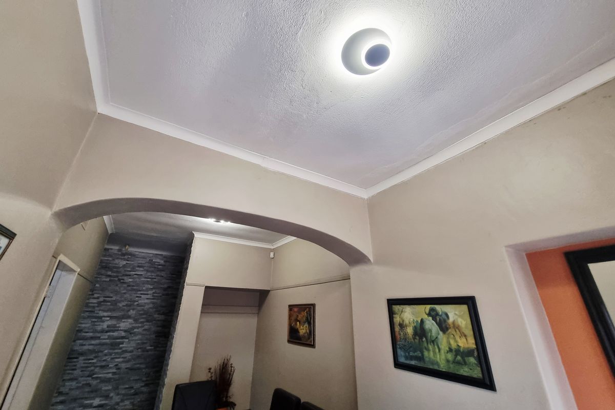 Interior view of a living area featuring an arched entryway, textured ceiling, and a decorative stone-cladding feature wall.