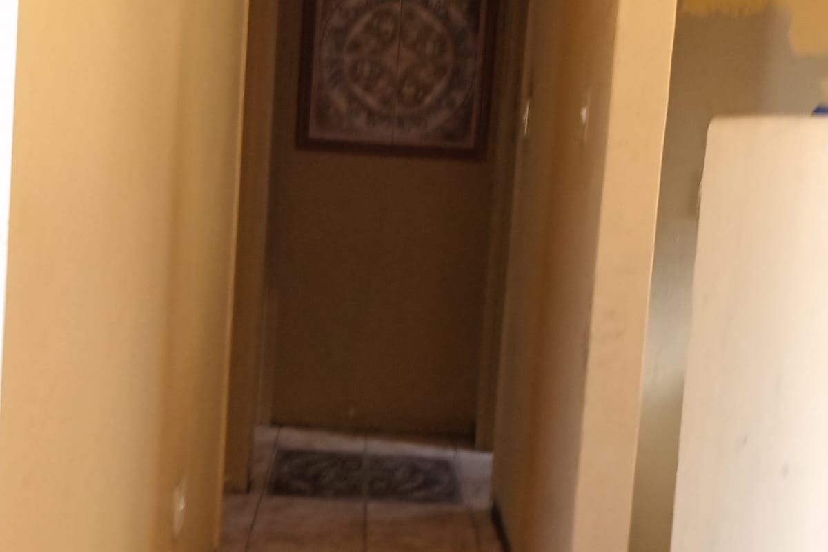 A narrow interior hallway featuring tiled flooring and neutral wall tones, providing access to adjacent rooms within the property.