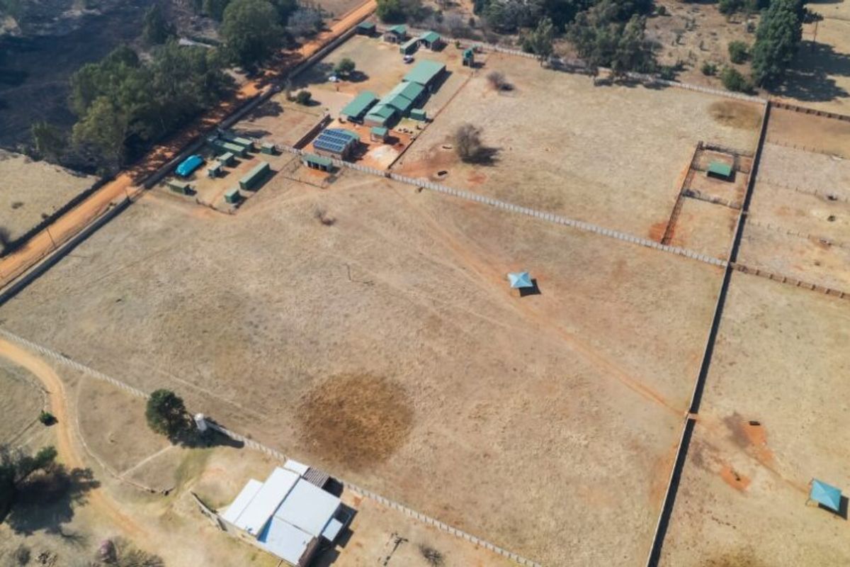 Aerial view of a large farm property featuring multiple outbuildings, fenced paddocks, solar infrastructure, and open grazing land.