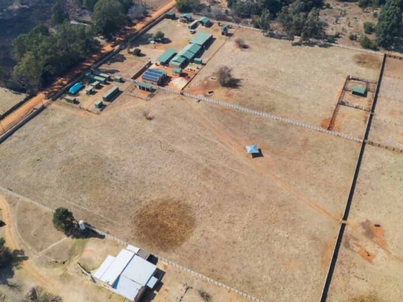 Aerial view of a large farm property featuring multiple outbuildings, fenced paddocks, solar infrastructure, and open grazing land.