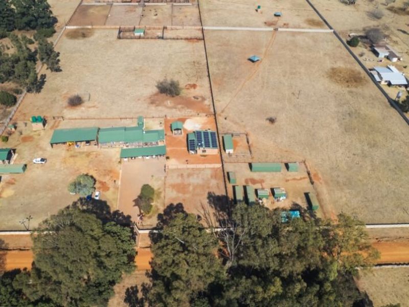 Aerial view of a large farm property featuring multiple outbuildings, solar panel installations, fenced paddocks, and extensive open land.