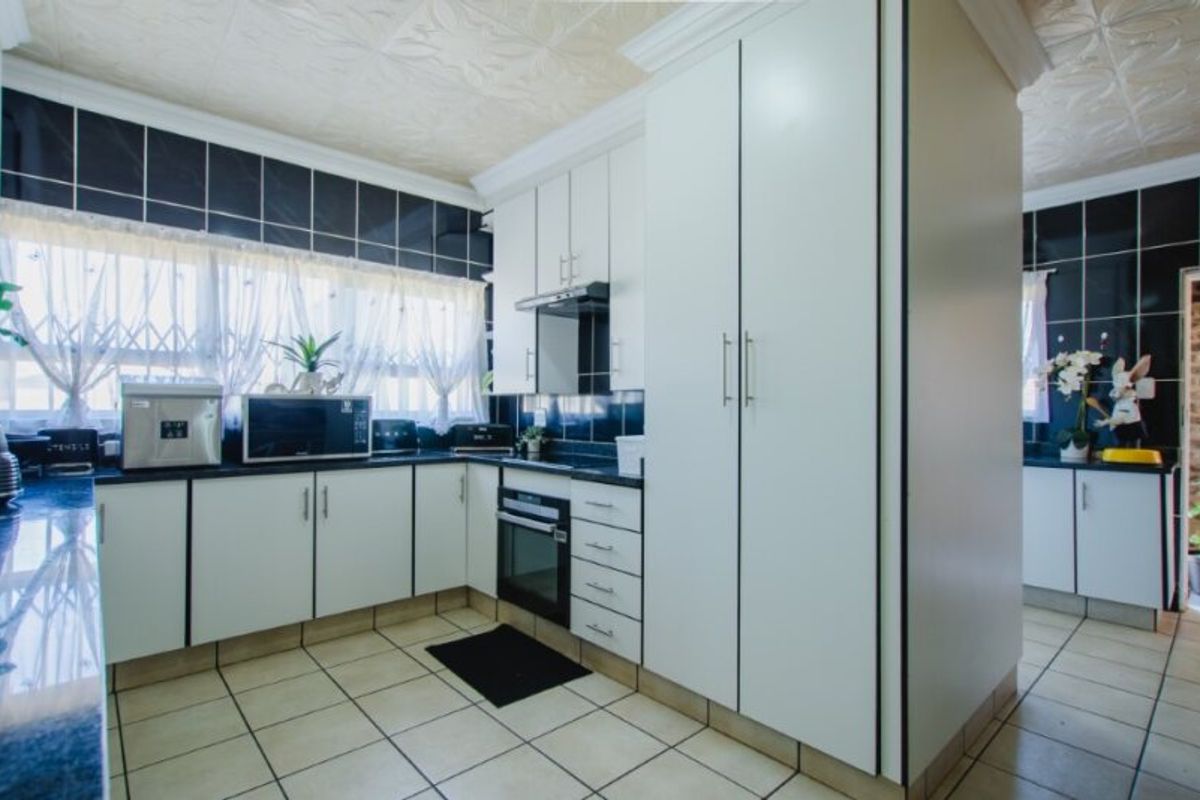 A functional kitchen featuring white cabinetry, dark tiled backsplash, built-in oven with extractor fan, and tiled flooring.