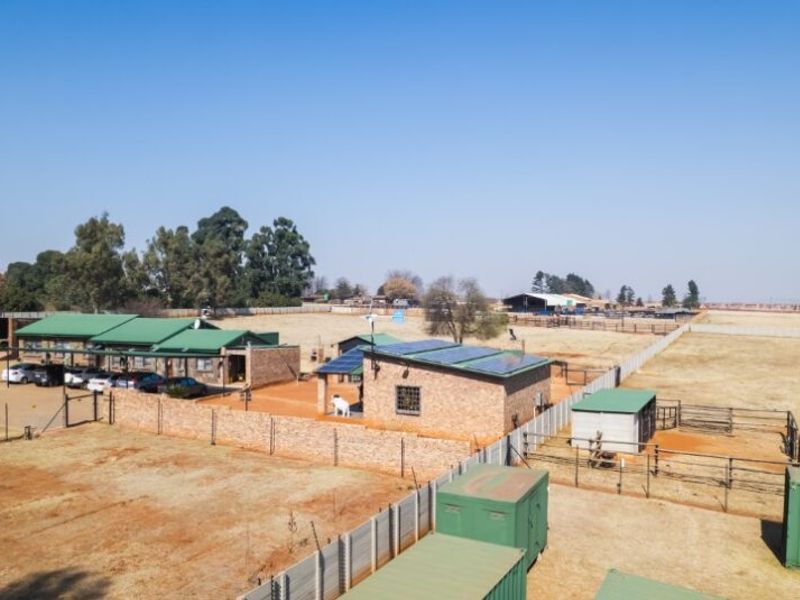 Aerial view of a farm property featuring multiple outbuildings, solar panel installations, fenced paddocks, and extensive open land.