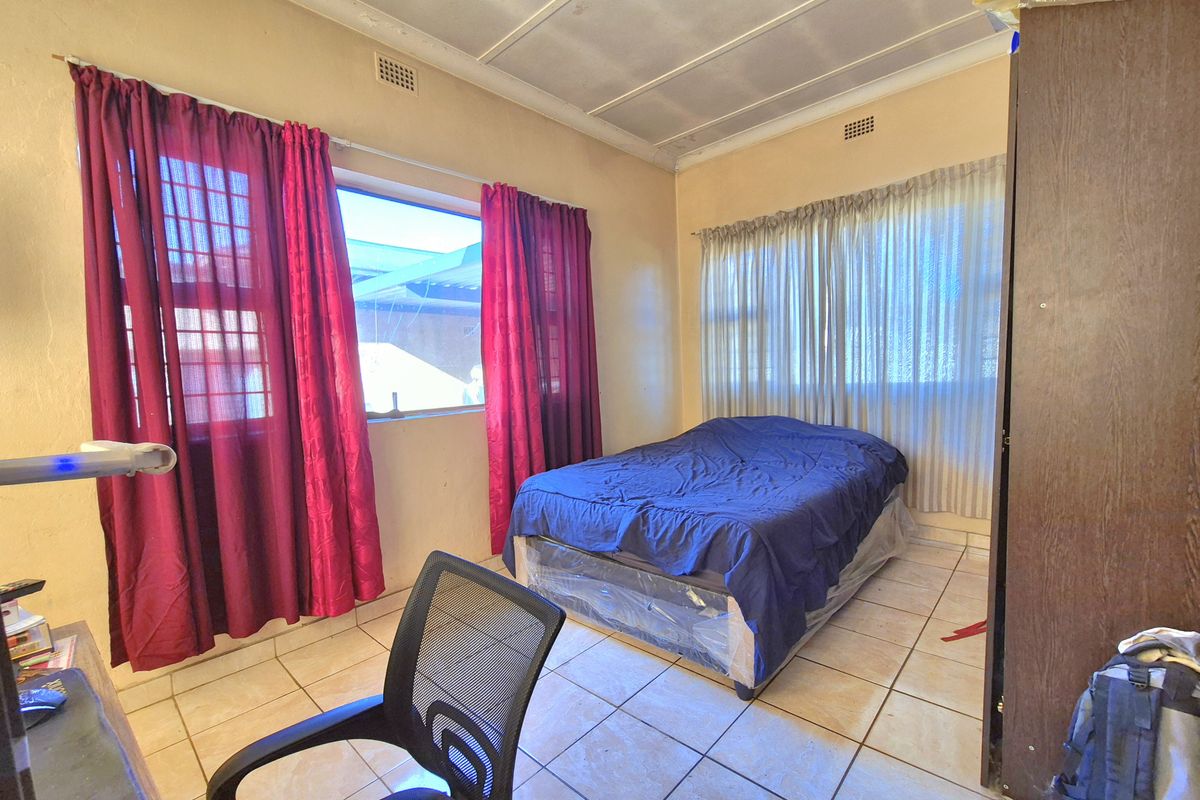 A bedroom featuring tiled flooring, large windows with curtains, and a basic ceiling finish.