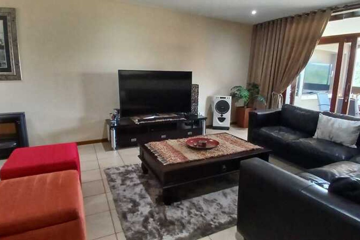 Spacious living room featuring tiled flooring, a built-in fireplace, and large sliding glass doors providing access to an outdoor patio area.