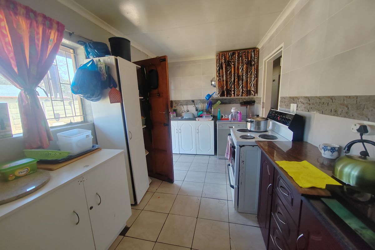 A functional kitchen featuring tiled flooring, built-in cabinetry, and a freestanding stove, offering a practical layout with potential for modernization.