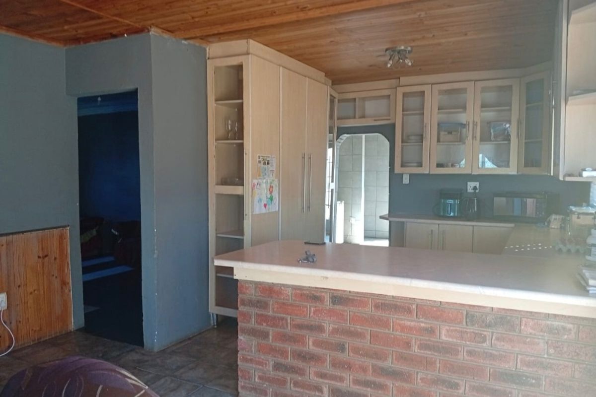 A functional kitchen featuring built-in cabinetry, a brick breakfast bar, and a timber-clad ceiling, offering a dated aesthetic with potential for modernization.